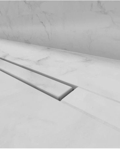 Caniveau drain invisible Carrodrain en acier inoxydable, finition élégante et moderne, intégré dans un sol en marbre blanc.